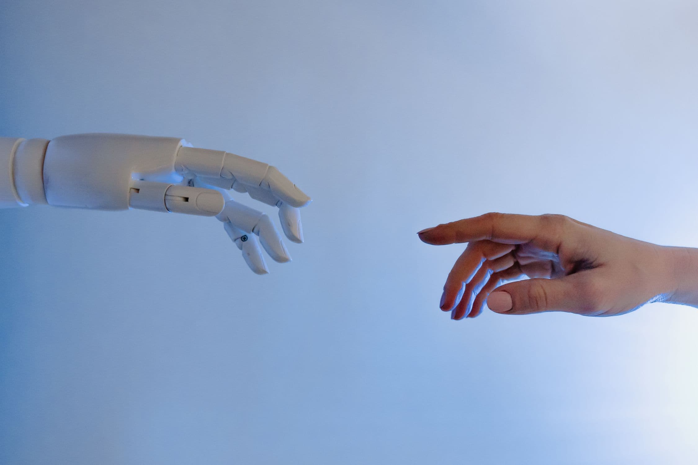 Human hand and robotic hand reaching toward each other - representing dexterous manipulation training data collection for robot AI systems