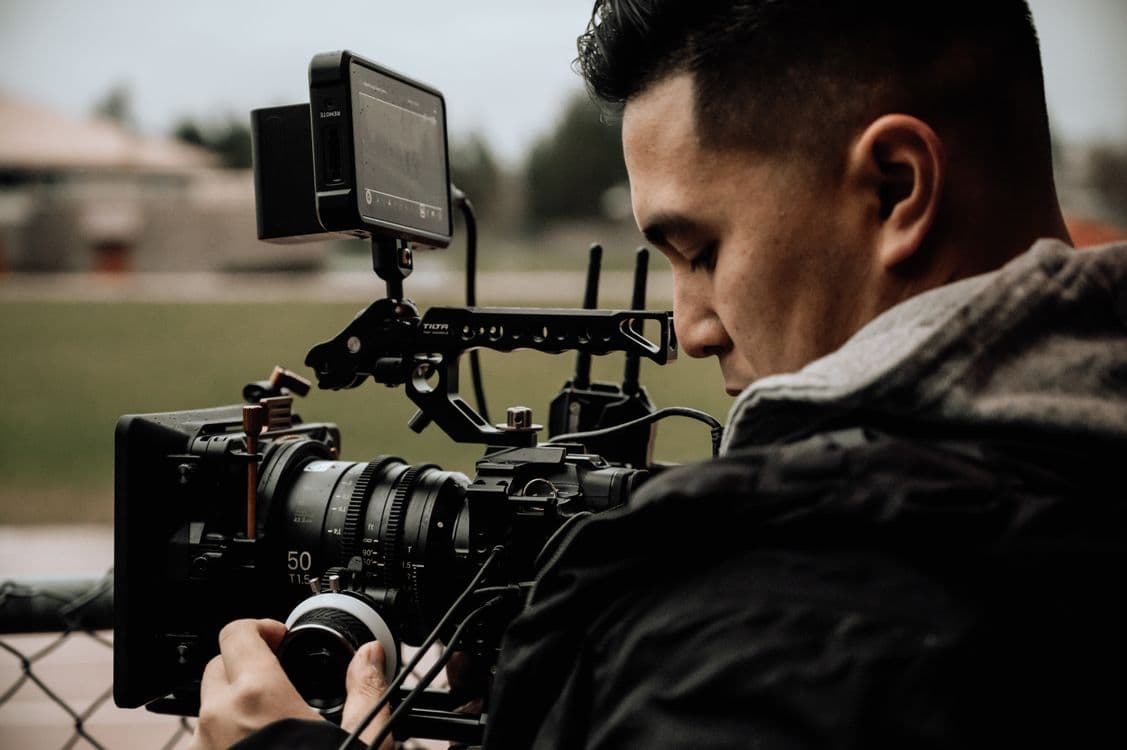 Camera operator using professional equipment for managed video data collection program outdoors