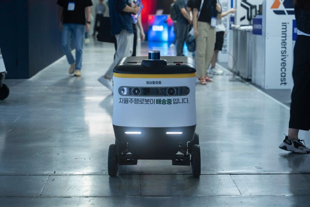 Autonomous delivery robot moving through a busy indoor venue among pedestrians, representing robot navigation training data for AMRs