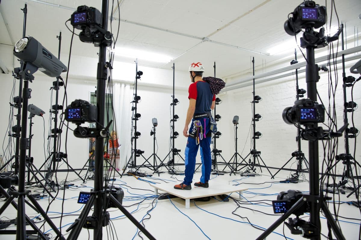 Person standing at the center of a synchronized multi-camera capture rig, illustrating multi-camera video collection for robotics training