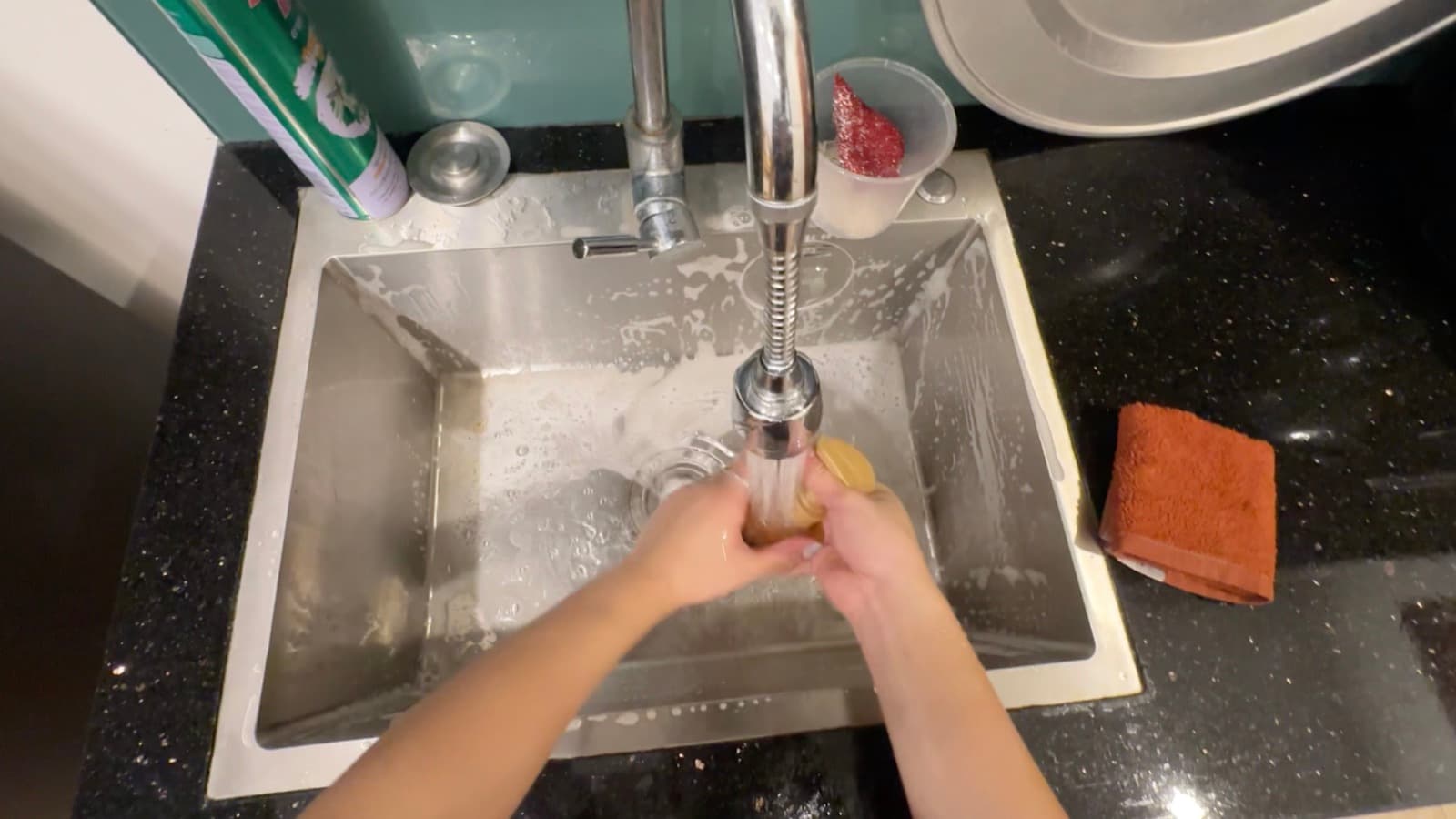 Khung hình thực tế từ camera đeo đầu: bồn rửa và đôi tay đang rửa đồ, không có khuôn mặt hay người khác