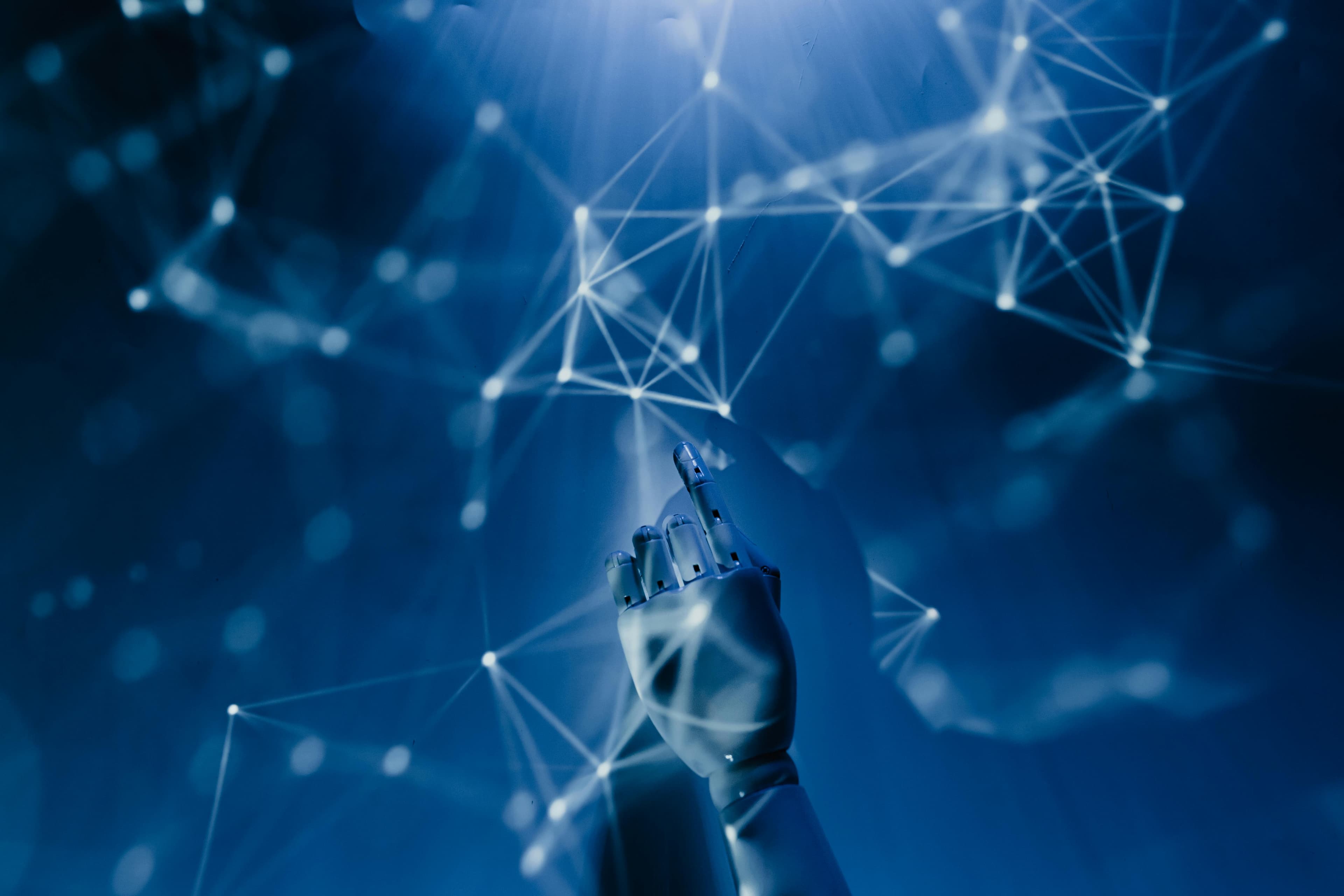 Robotic hand reaching into a glowing network of connected nodes